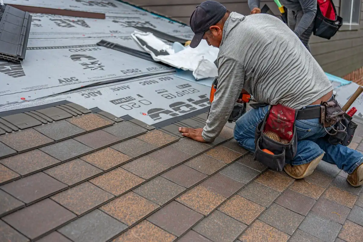 Roofing installer fastening shingles over new underlayment in Laredo, TX